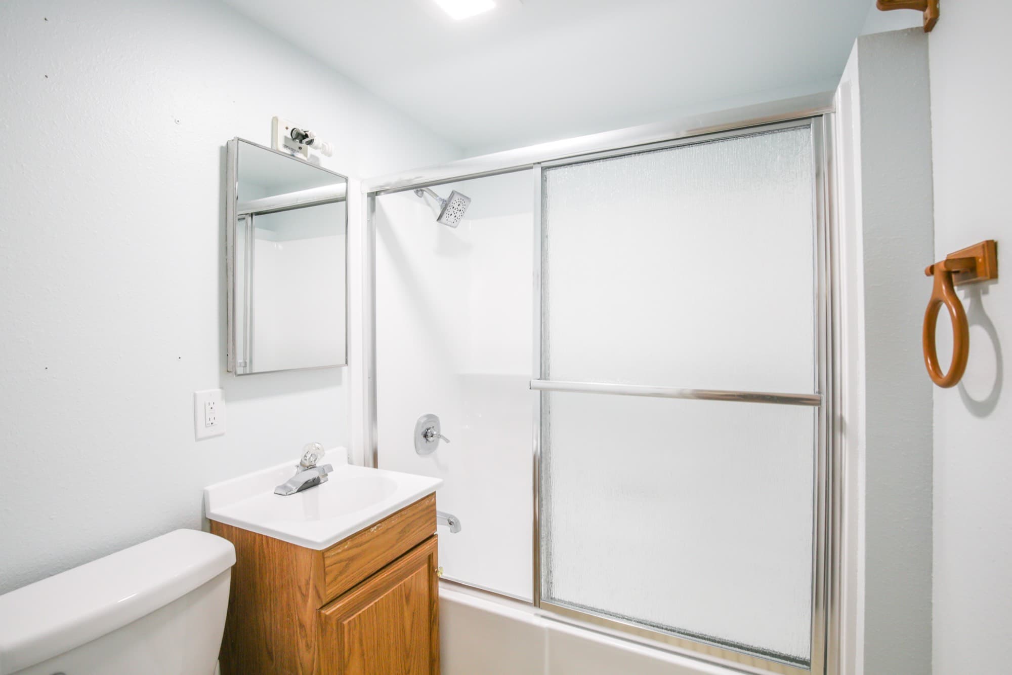 Full bathroom with tub-shower combo, wood vanity, and medicine cabinet