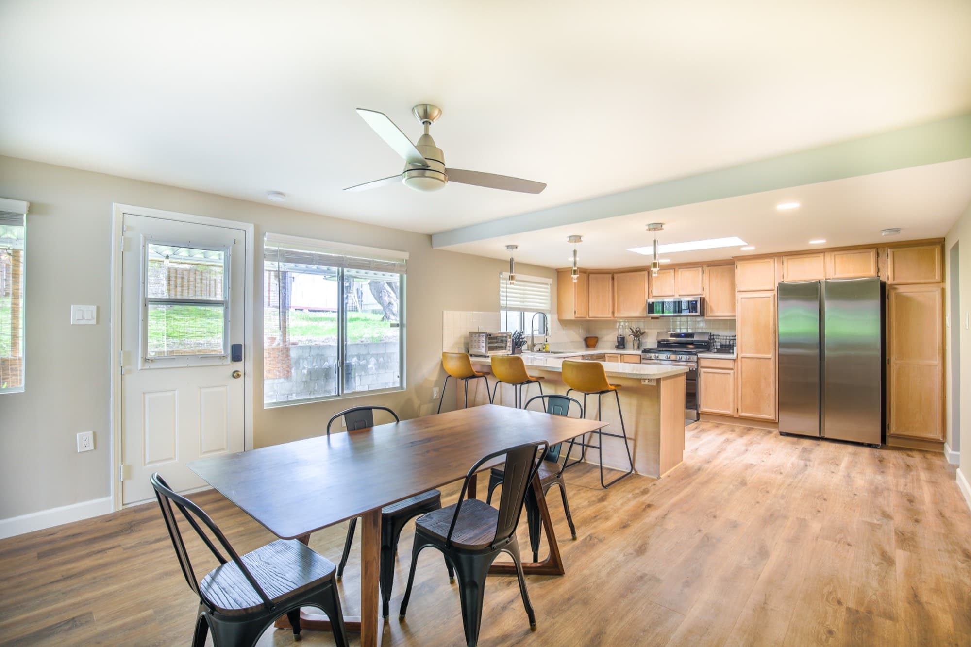 Open-plan dining area and kitchen with island, pendant lights, and ceiling fan