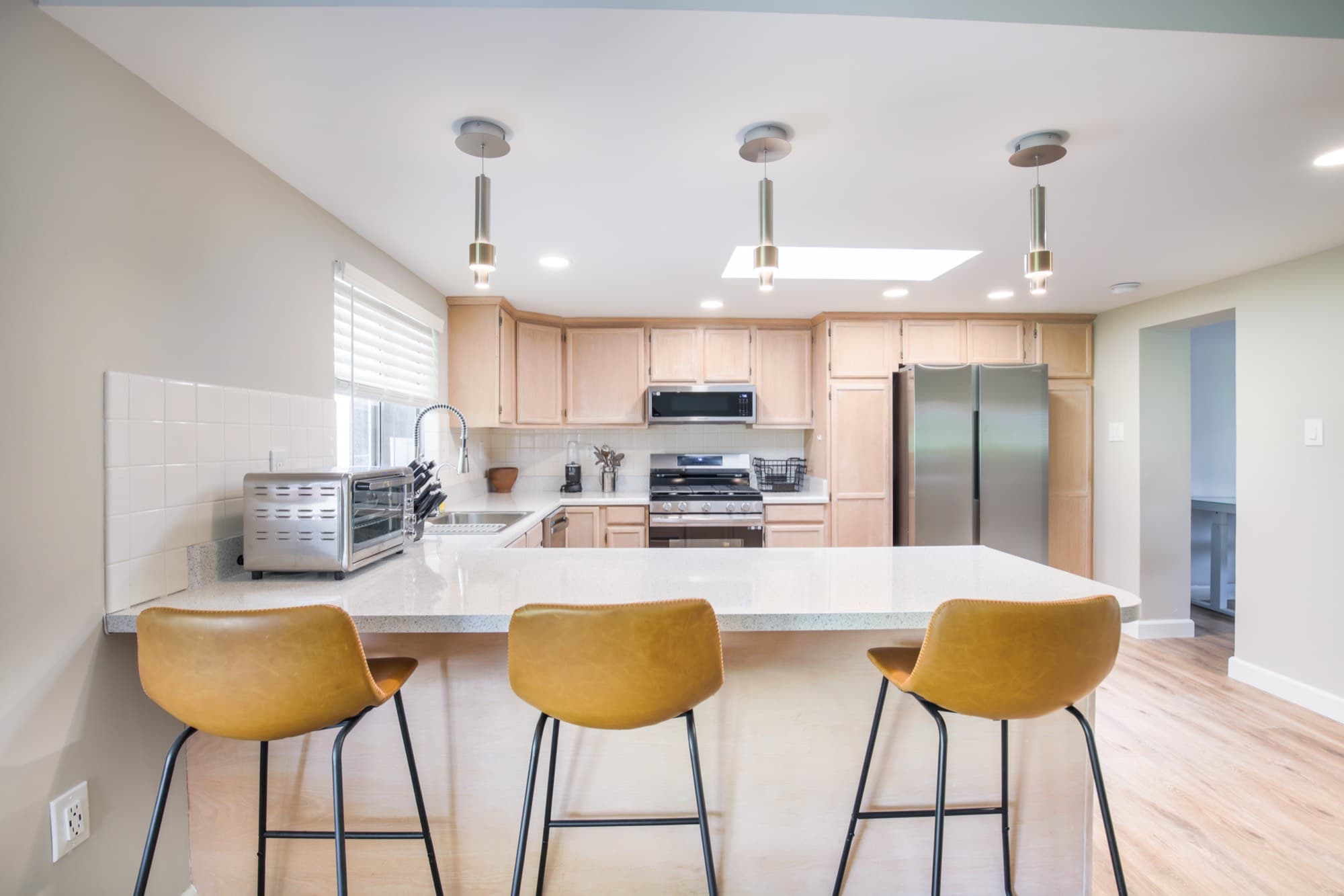Kitchen with quartz countertops, bar seating, pendant lights, and stainless steel appliances