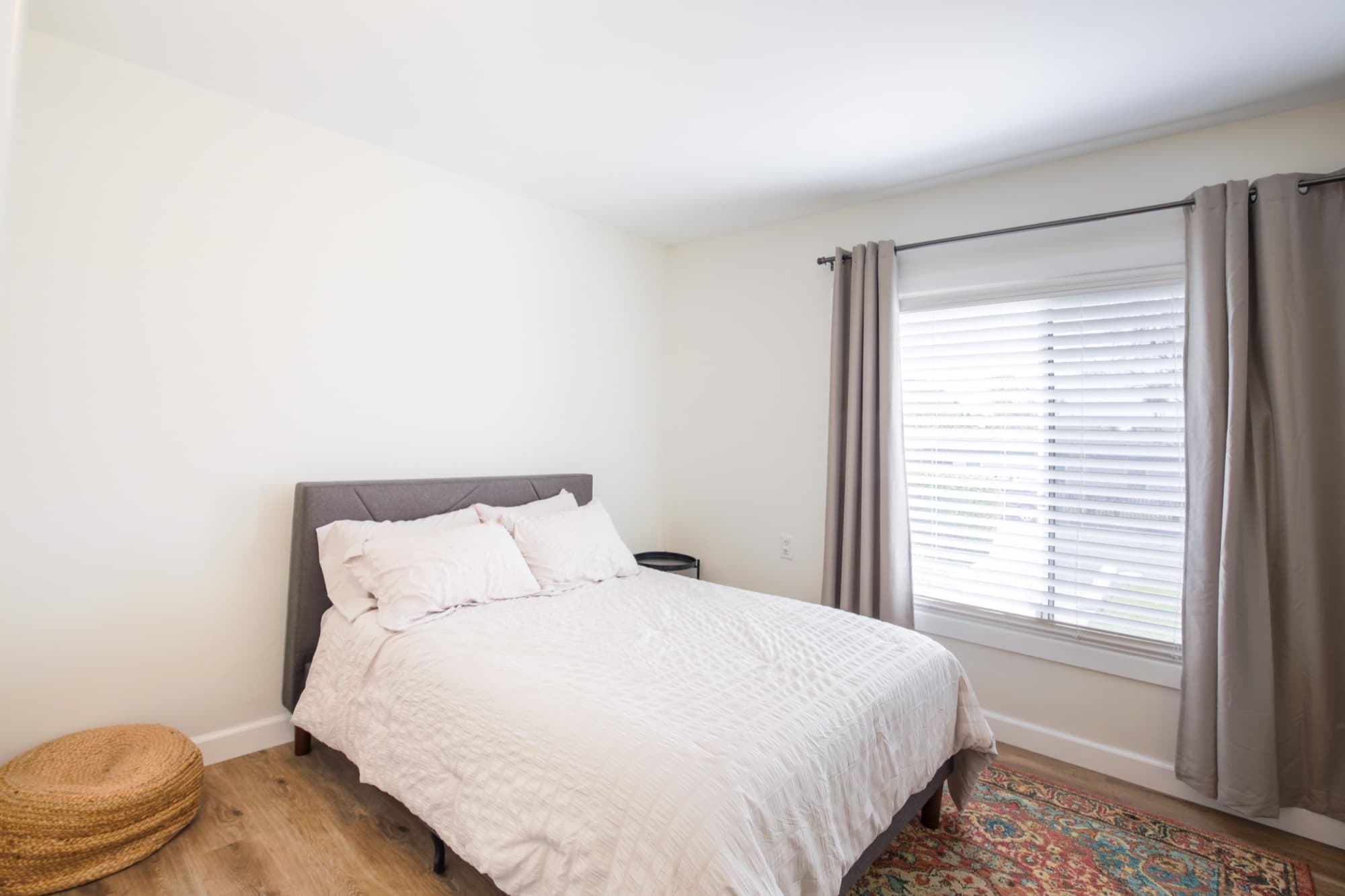 Guest bedroom with queen bed, colorful Persian rug, and natural light