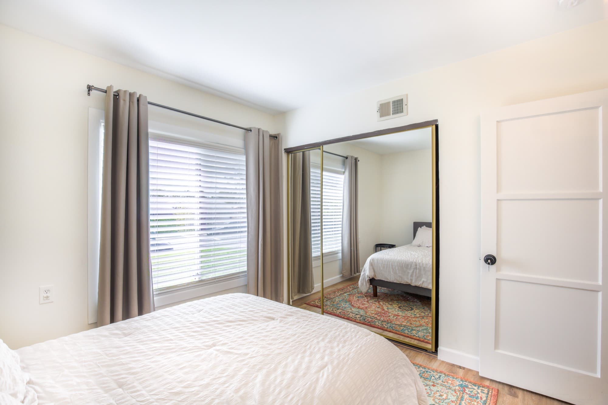 Guest bedroom with mirrored sliding closet and natural light