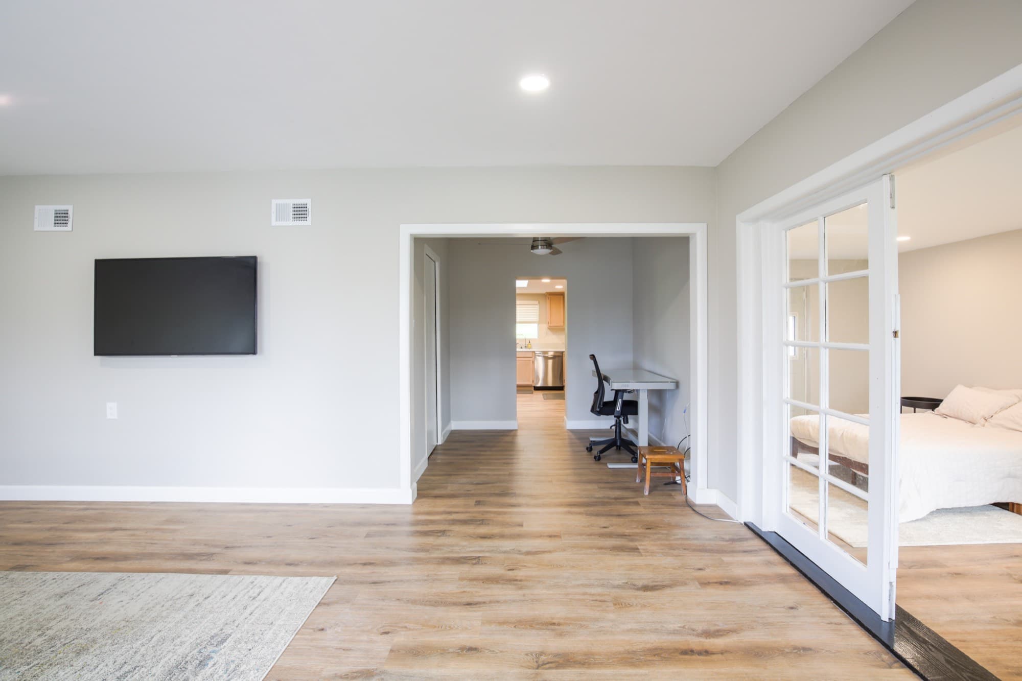 Open living space with TV, office nook, and French doors to bedroom